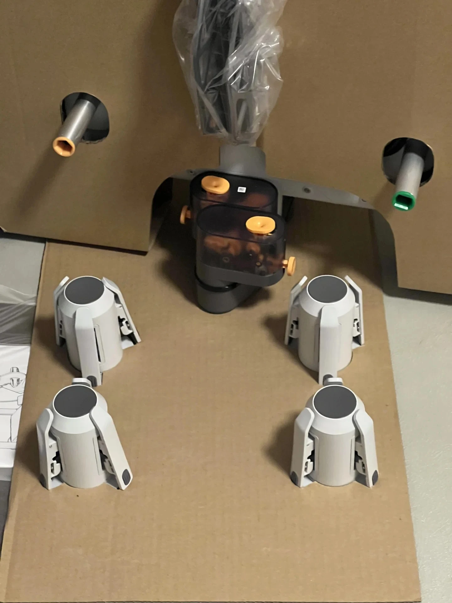 Four white spool holders and the central feeder assembly of an AMS Lite module arranged in a cardboard shipping insert.