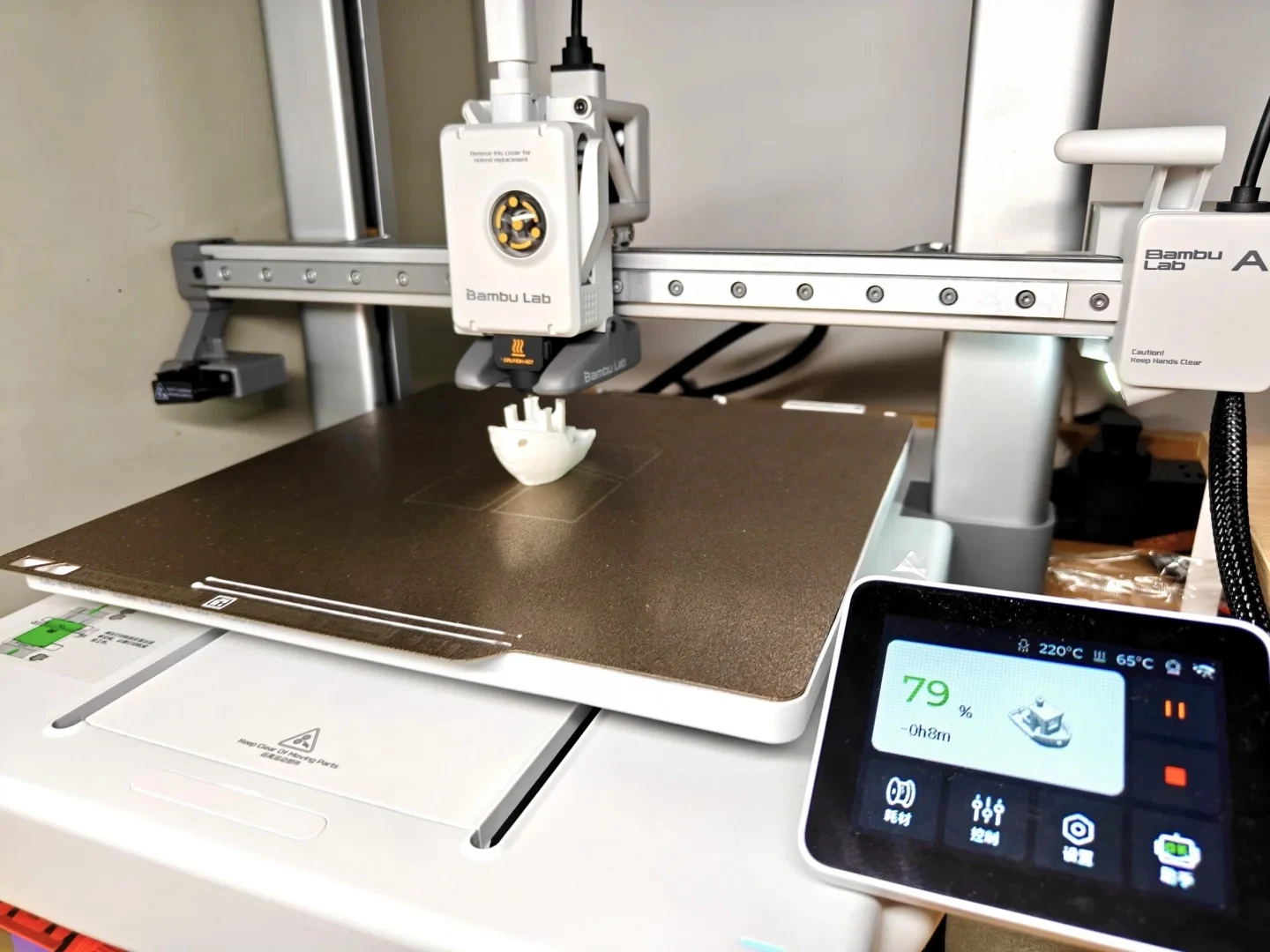 A Bambu Lab A1 3D printer printing a white Benchy test boat on its textured build plate, with the touchscreen display showing 79 percent progress.