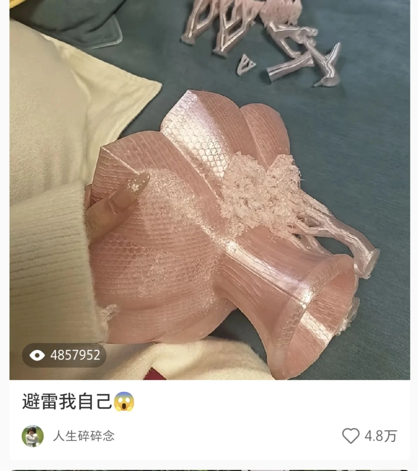 Screenshot of a social media post showing a person holding a 3D-printed translucent pink vase or flower-shaped object with tangled support filament stuck to the bottom, with loose 3D-printed support trees lying nearby on a blanket.