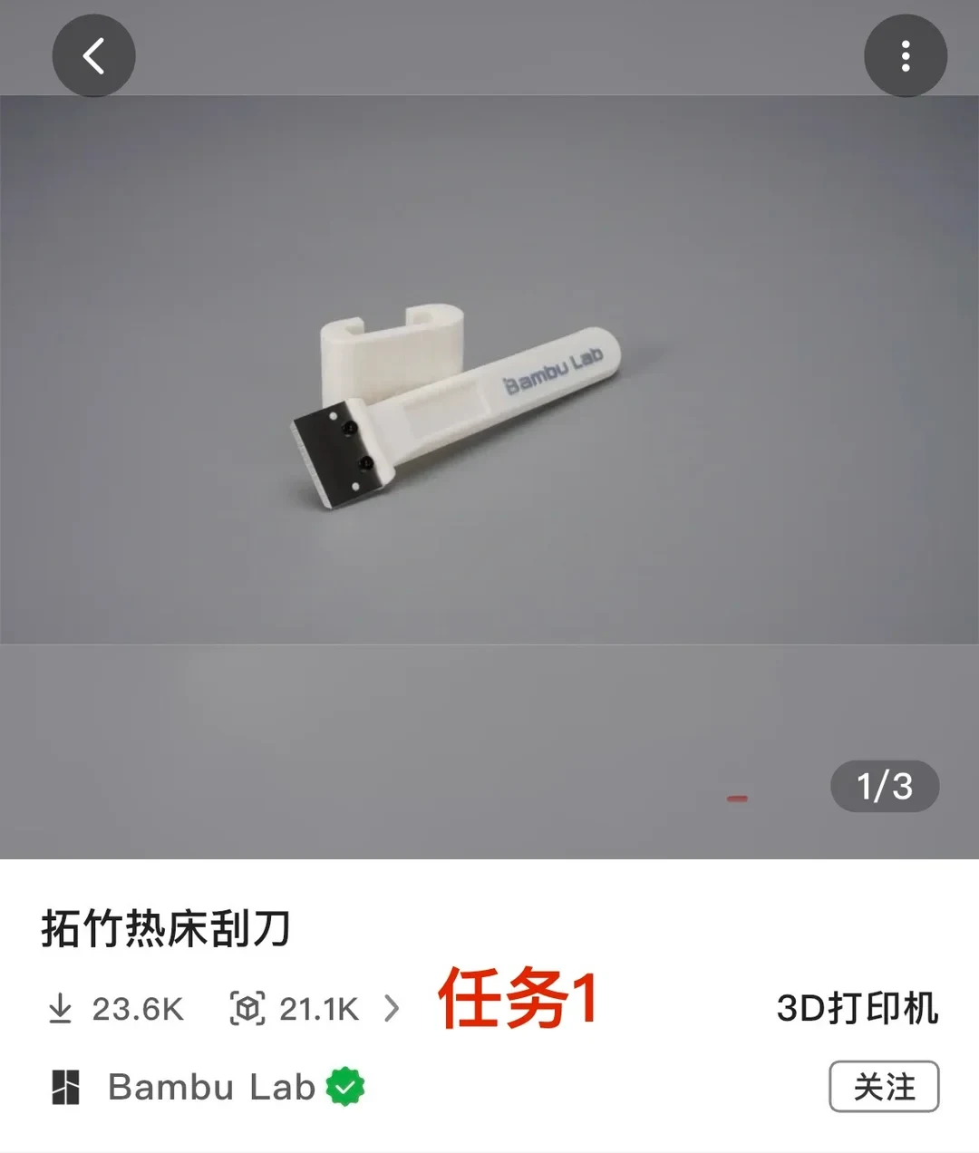 A product page screenshot for a Bambu Lab 3D printable heated bed scraper. The upper half shows a photo of the white plastic scraper with a metal blade and a holder stand. Below the photo, the title reads '拓竹热床刮刀' (Bambu Lab Heated Bed Scraper) along with download and like counts, a red overlay reading '任务1', the category '3D打印机' (3D Printer), and the verified creator Bambu Lab with a '关注' (Follow) button.