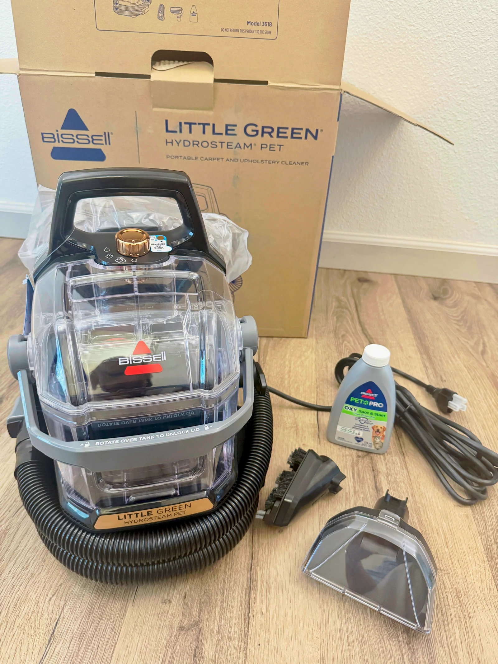 The Little Green HydroSteam Pet unboxed with hose tools and cleaning formula.