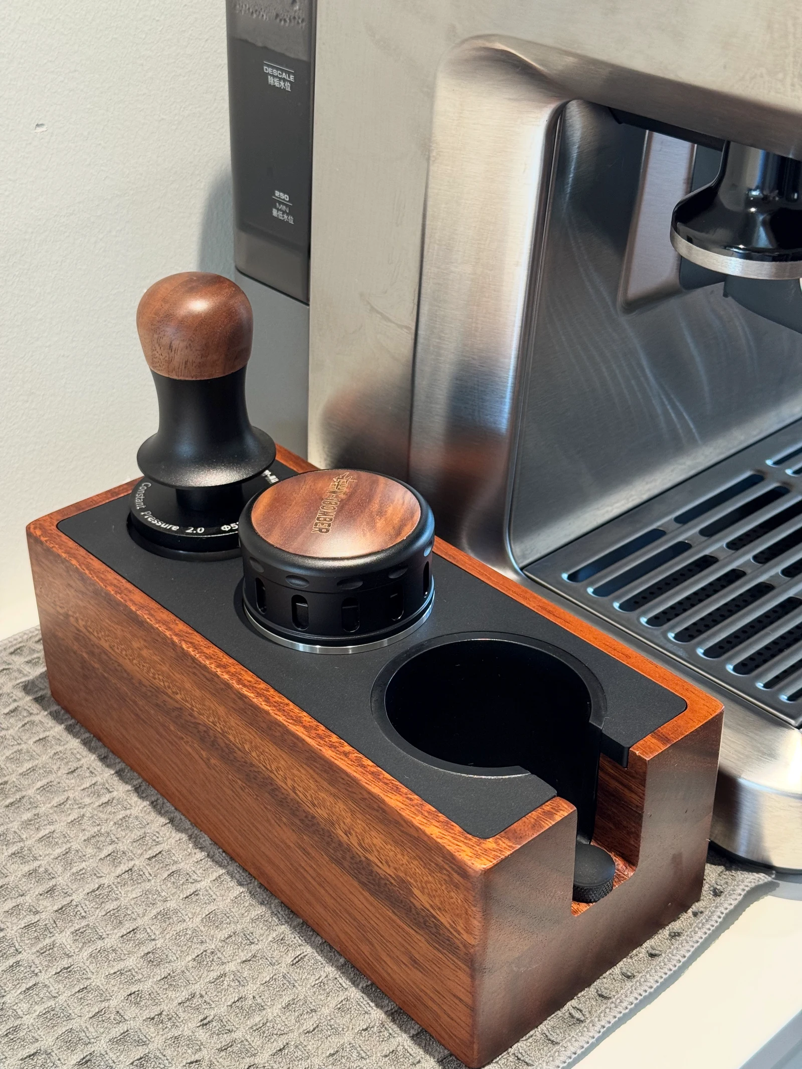The constant-force tamper and distributor in their stand.