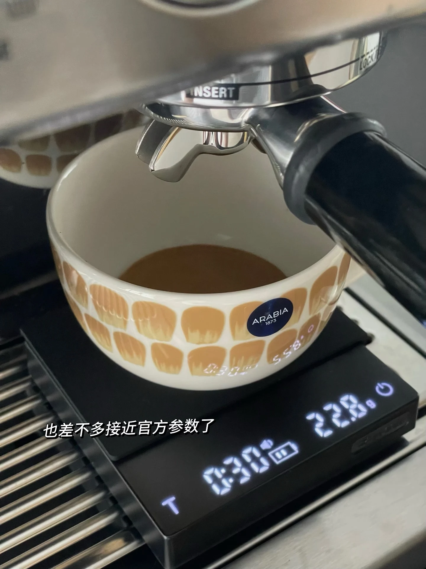 An espresso cup on a scale beneath the group head.