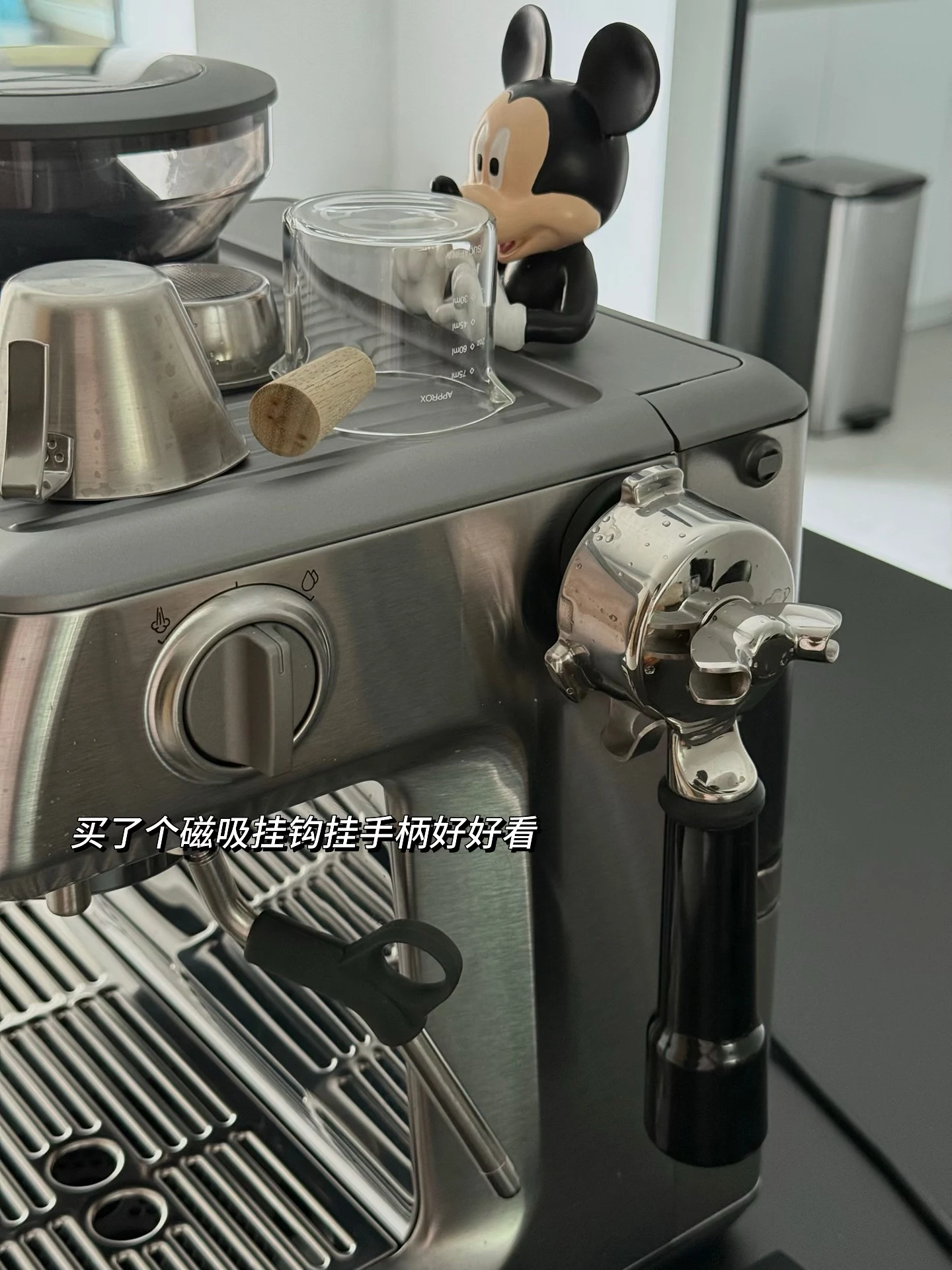 A magnetic hook supporting the portafilter beside the machine.