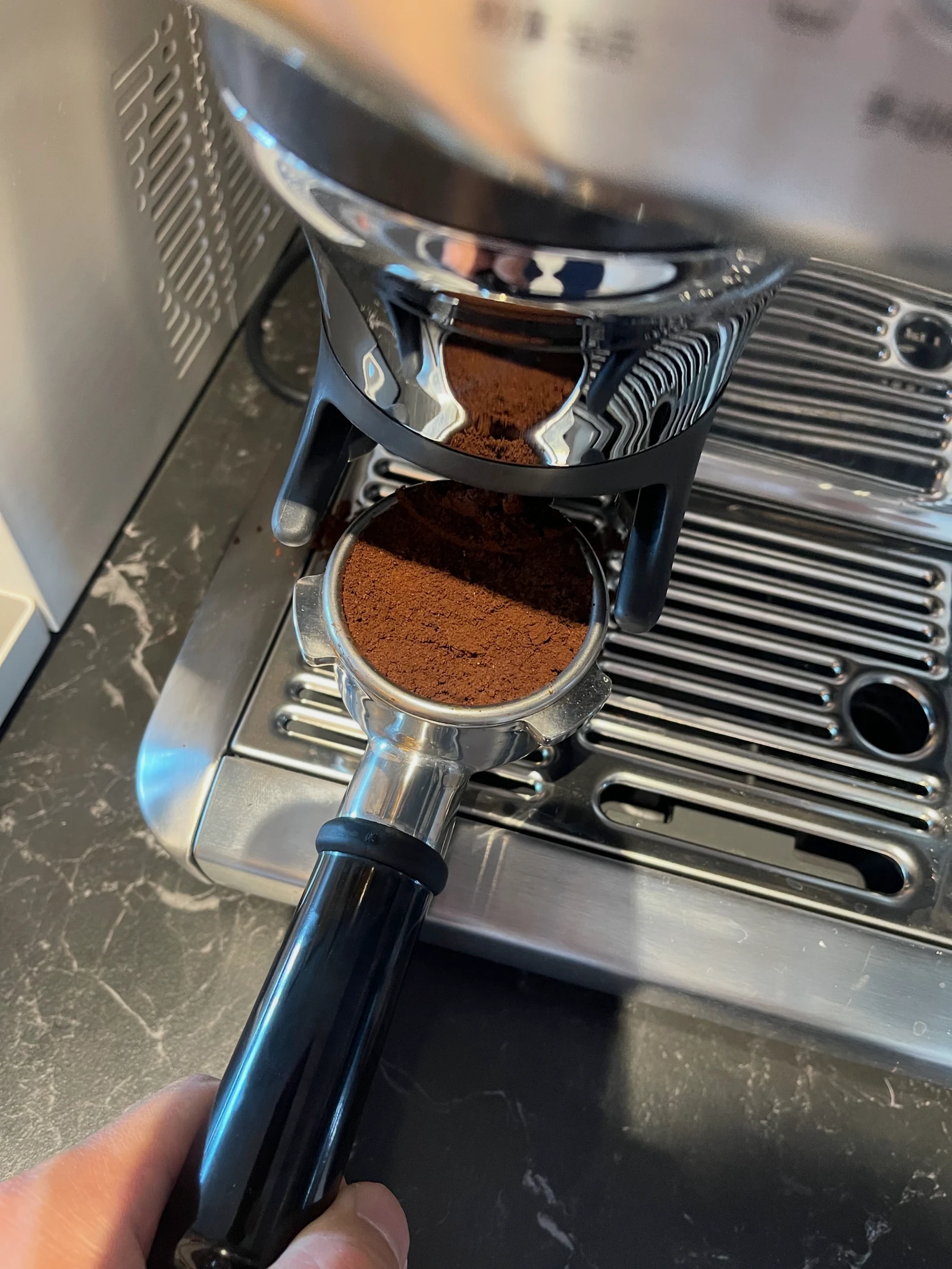Fresh grounds in the portafilter beneath the dosing outlet.