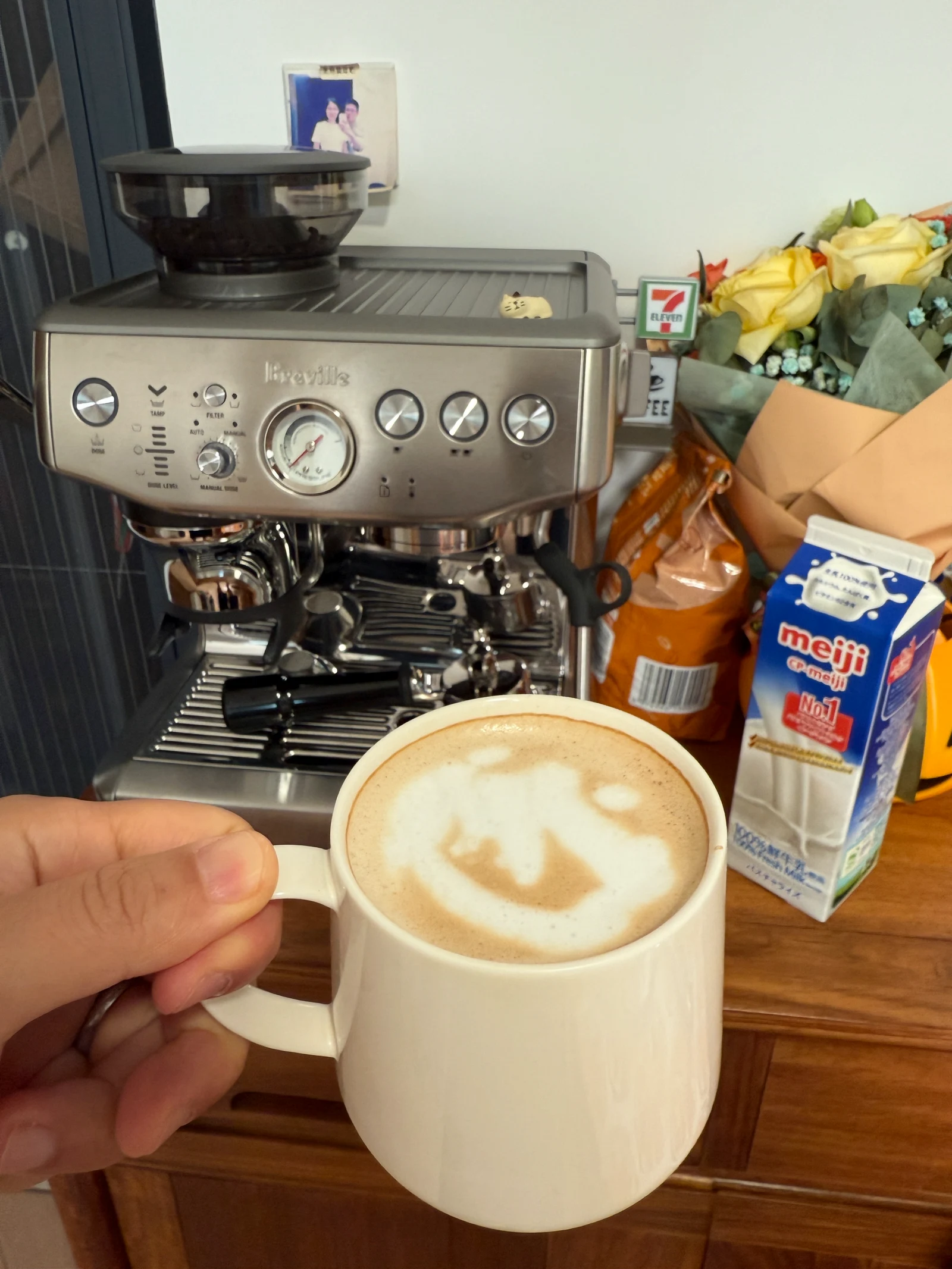 The owner holding a milk coffee in front of the machine.