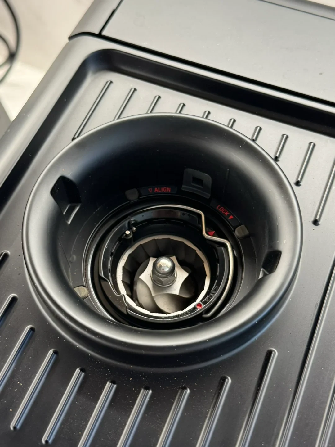 Top-down view of the conical burr grinder chamber on a black Breville 880 espresso machine with the hopper removed.