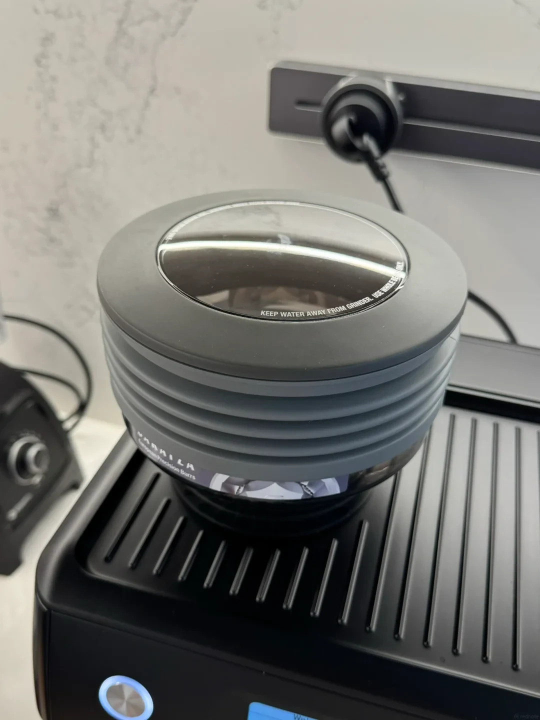 Close-up of a silicone bellows hopper attachment mounted on the grinder of a Breville 880 espresso machine.