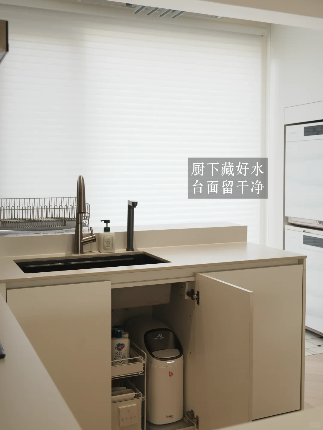 A modern kitchen counter with an undermount sink and open cabinet doors revealing an under-sink water filtration appliance installed underneath, keeping the countertop tidy.