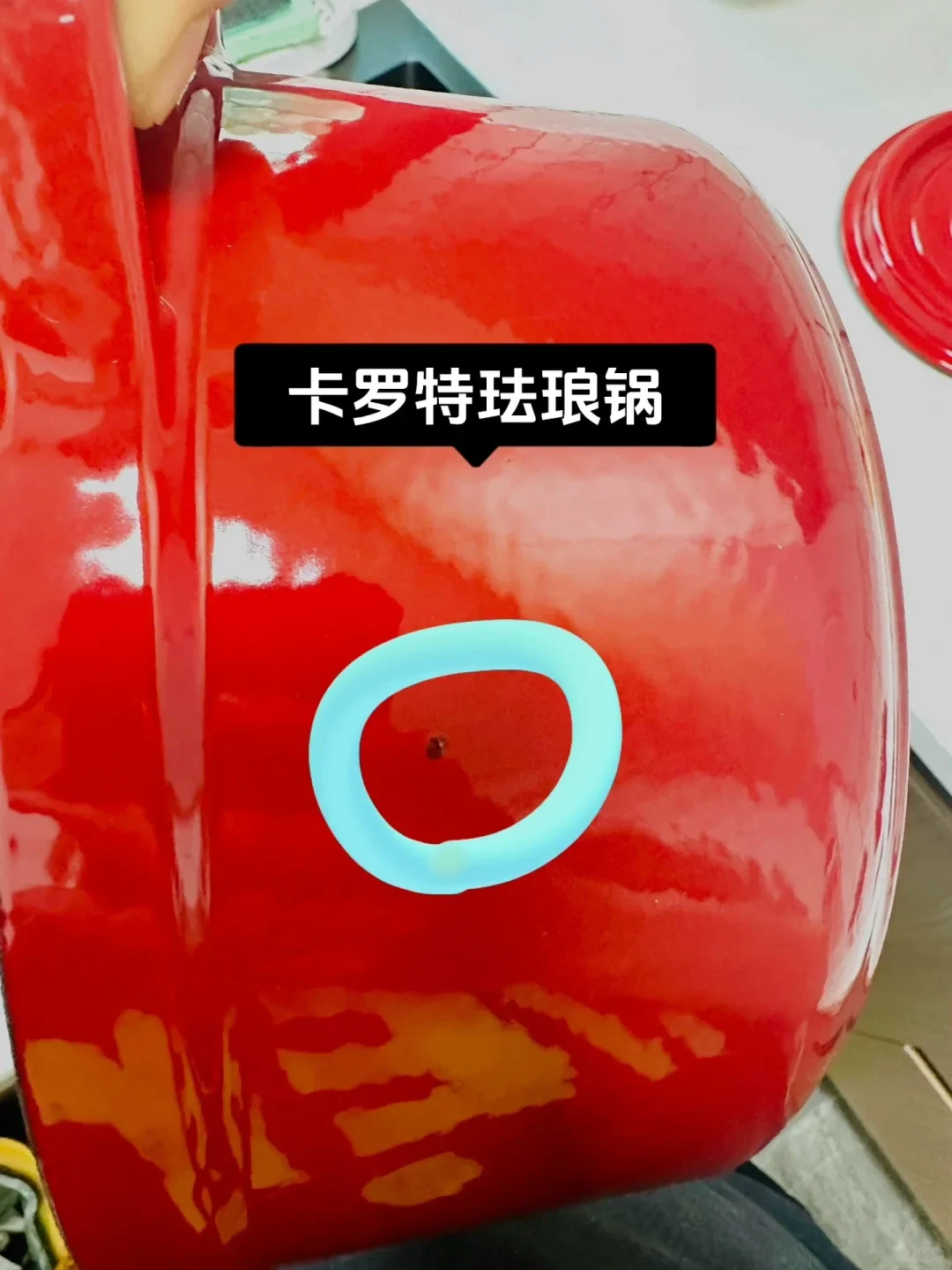 Close-up of a red enamel cooking pot highlighting a small blemish circled in blue with a text label above it.