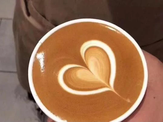 Top-down view of a cup of latte featuring heart-shaped latte art atop golden brown crema.