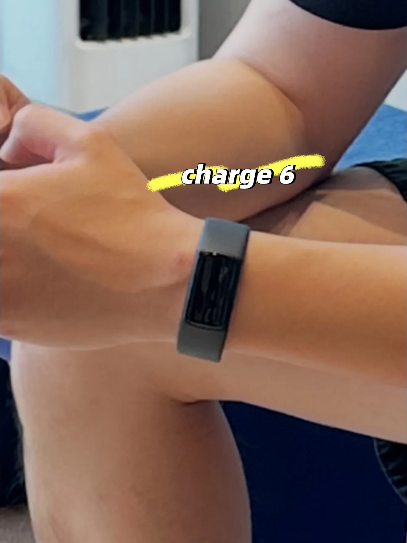Close-up of a person's wrist wearing a black Charge 6 fitness tracker with 'charge 6' highlighted in yellow above it.
