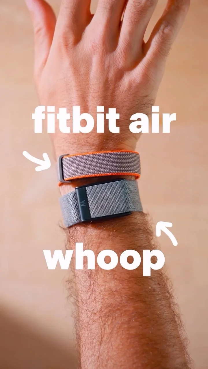 A person's wrist wearing two fitness trackers side by side: a slim grey strap with orange trim labeled 'fitbit air' above, and a wider grey woven strap labeled 'whoop' below.