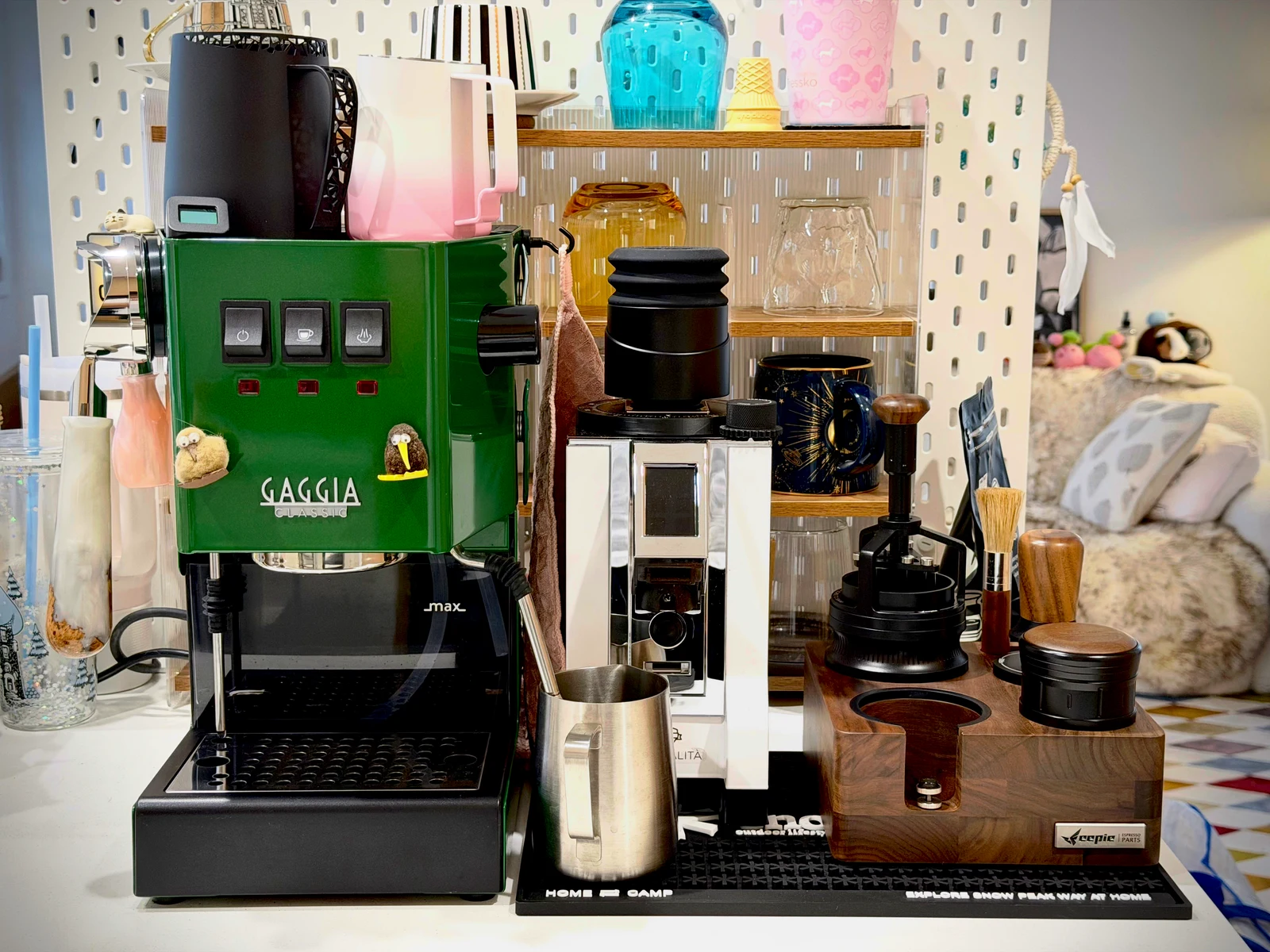 The green E24 beside a grinder and an extensive set of coffee accessories.