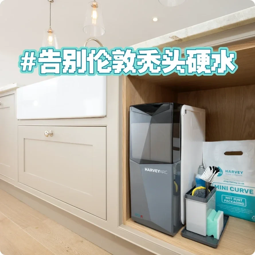 A modern kitchen island with an open oak storage cubby next to white drawers and a sink. Inside the cubby is a compact gray and white HarveyArc water softener unit, a caddy with cleaning sponges and brushes, and a bag of Harvey water softener salt. Overlaid at the top is bold Chinese text formatted as a hashtag.