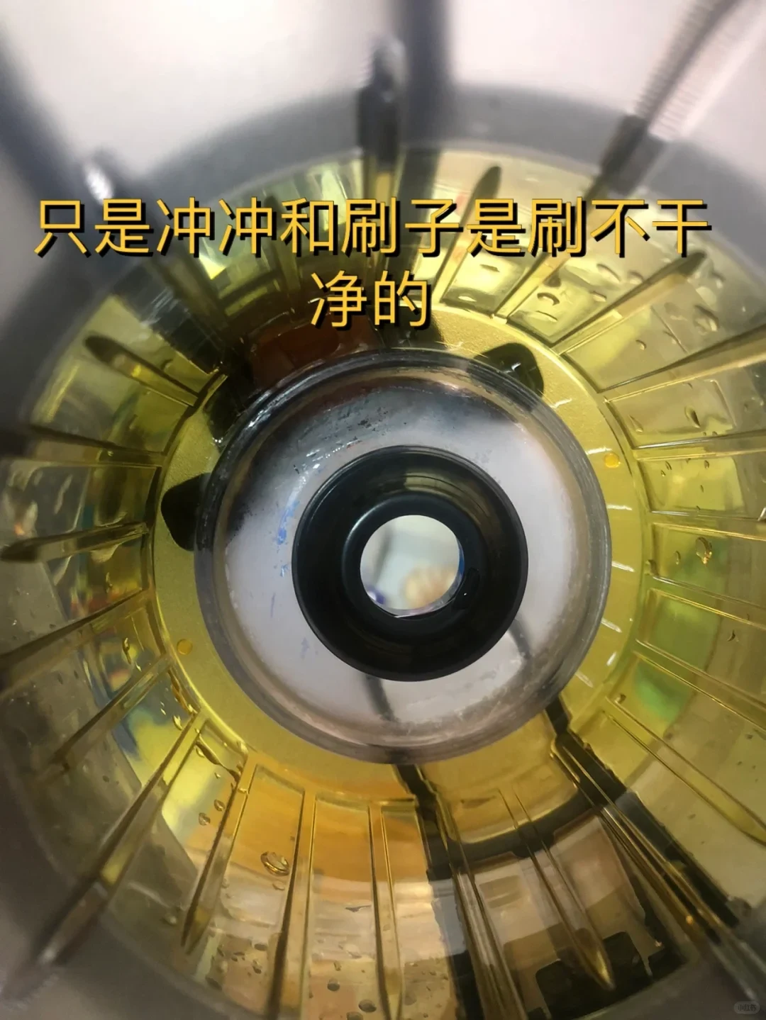 Inside the Hurom juicer chamber, pale residue surrounds the central opening and droplets remain in the radial grooves. The Chinese overlay says rinsing and brushing do not get it clean.
