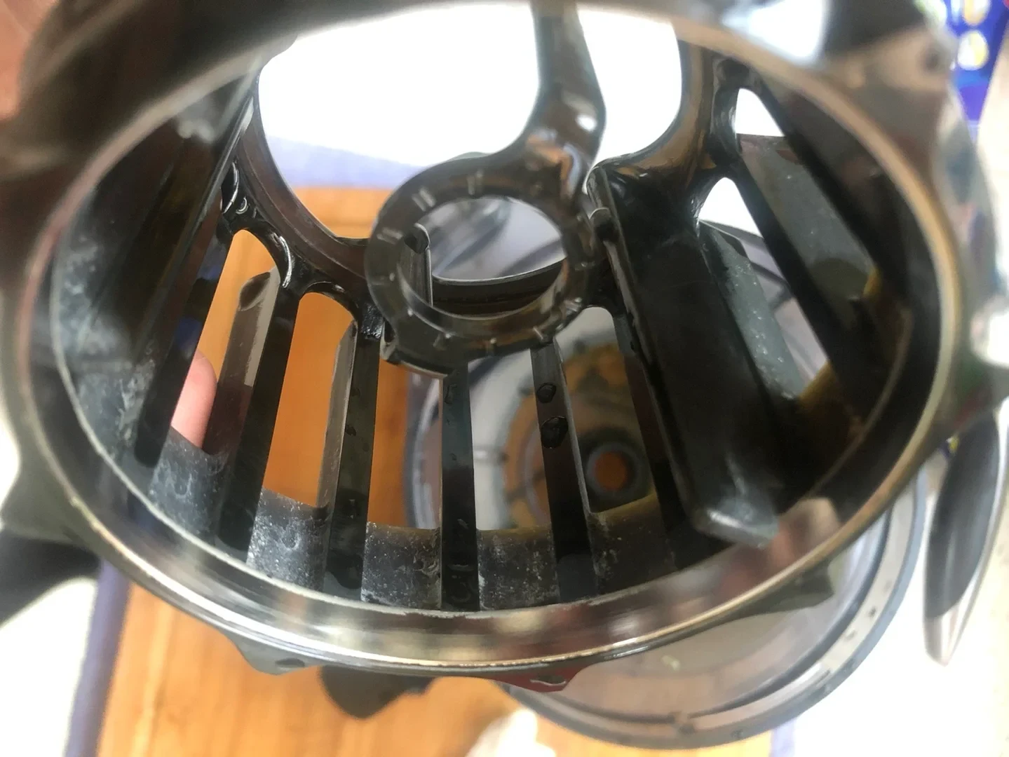 Close-up of the Hurom juicer’s black slotted Multi-screw component, with pale residue around the rim and a fingertip behind it.