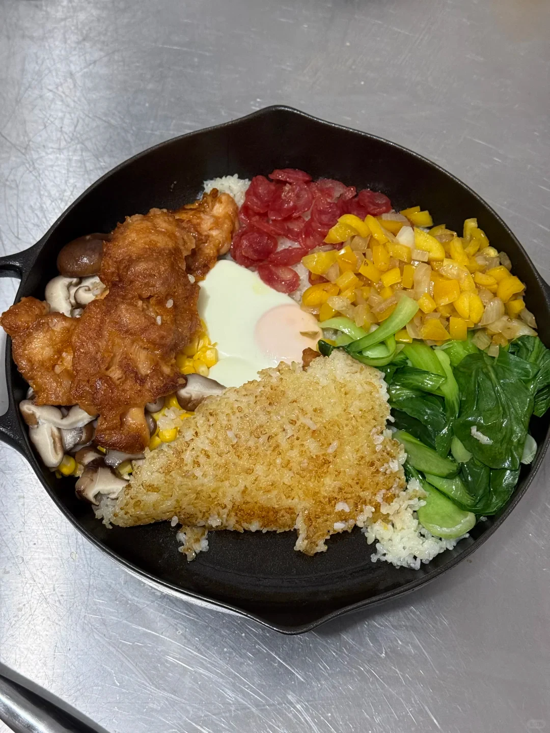 A skillet meal with rice, an egg, sliced meat and vegetables.