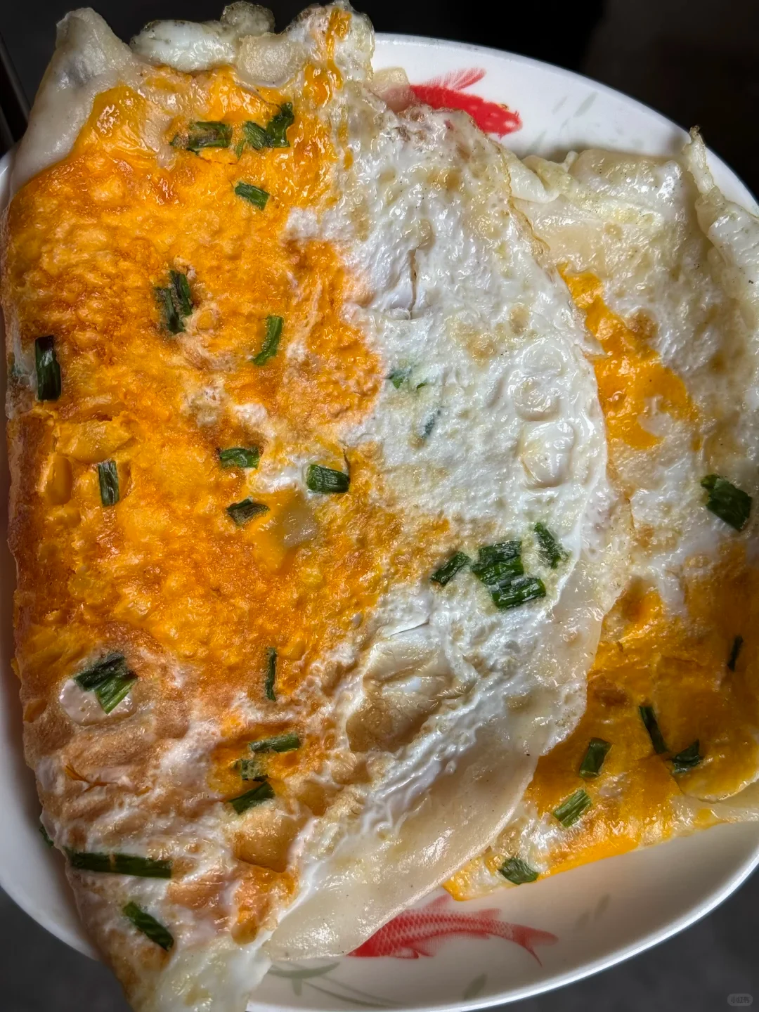 Fried eggs topped with chopped greens on a white patterned plate.