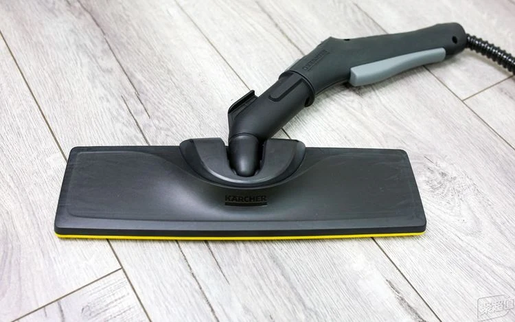 High-angle view of the black Kärcher floor nozzle attached directly to the steam handle on light wood-grain flooring.
