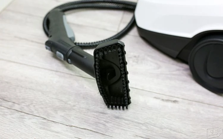 Close-up of the black hand brush nozzle attachment connected to the steam gun handle and hose of the Kärcher SC3 steam cleaner on a light-colored floor.