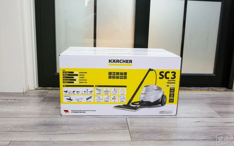 Unopened Kärcher SC3 EasyFix Premium steam cleaner retail box on a wooden floor, showing the cleaner, accessories, and a printed specifications panel.