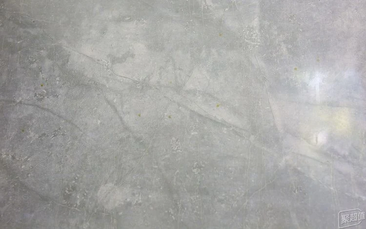 Close-up of light gray marble-patterned kitchen wall tiles with faint scattered yellow grease spots.