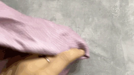 A hand peeling a light purple microfiber cloth away from a steam cleaner head.
