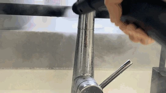 Using the steam cleaner's nozzle to blast hot steam onto a chrome faucet to remove limescale.
