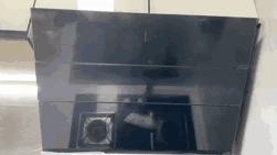 A black glass slanted kitchen range hood mounted over a gas stovetop.