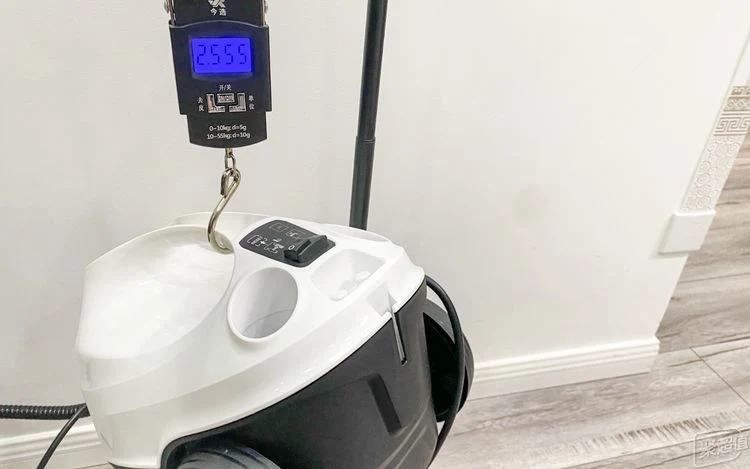 A digital hanging scale weighing the Kärcher SC3 steam cleaner filled with water, showing a measurement of 2.555 kg.