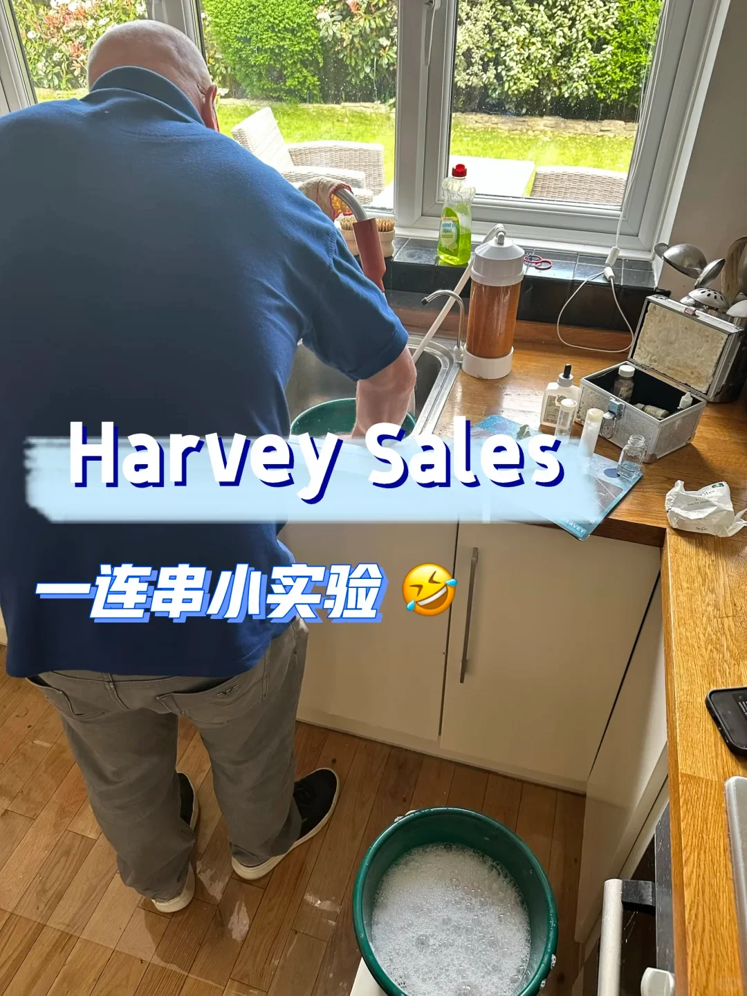 A man in a blue shirt seen from behind stands at a kitchen sink conducting water tests, with testing vials, an open kit, and a bucket of sudsy water nearby. Overlay text reads 'Harvey Sales' and Chinese text underneath with a laughing emoji.