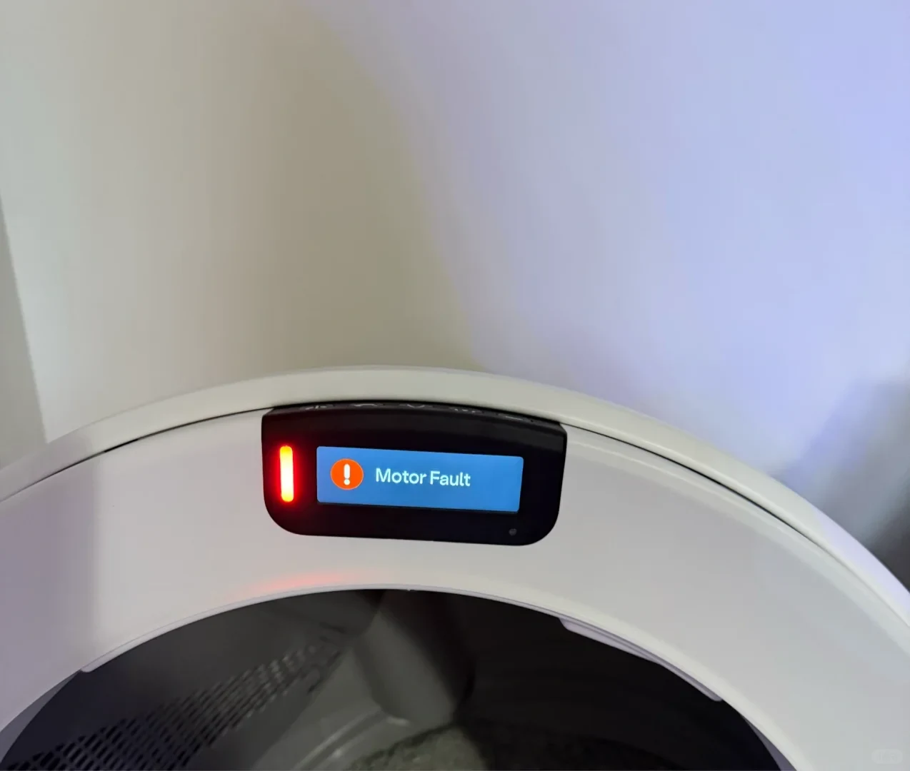 Close-up of the control module on an automatic cat litter box, displaying a vertical red warning light and an illuminated digital screen reading 'Motor Fault' next to an orange exclamation point icon.