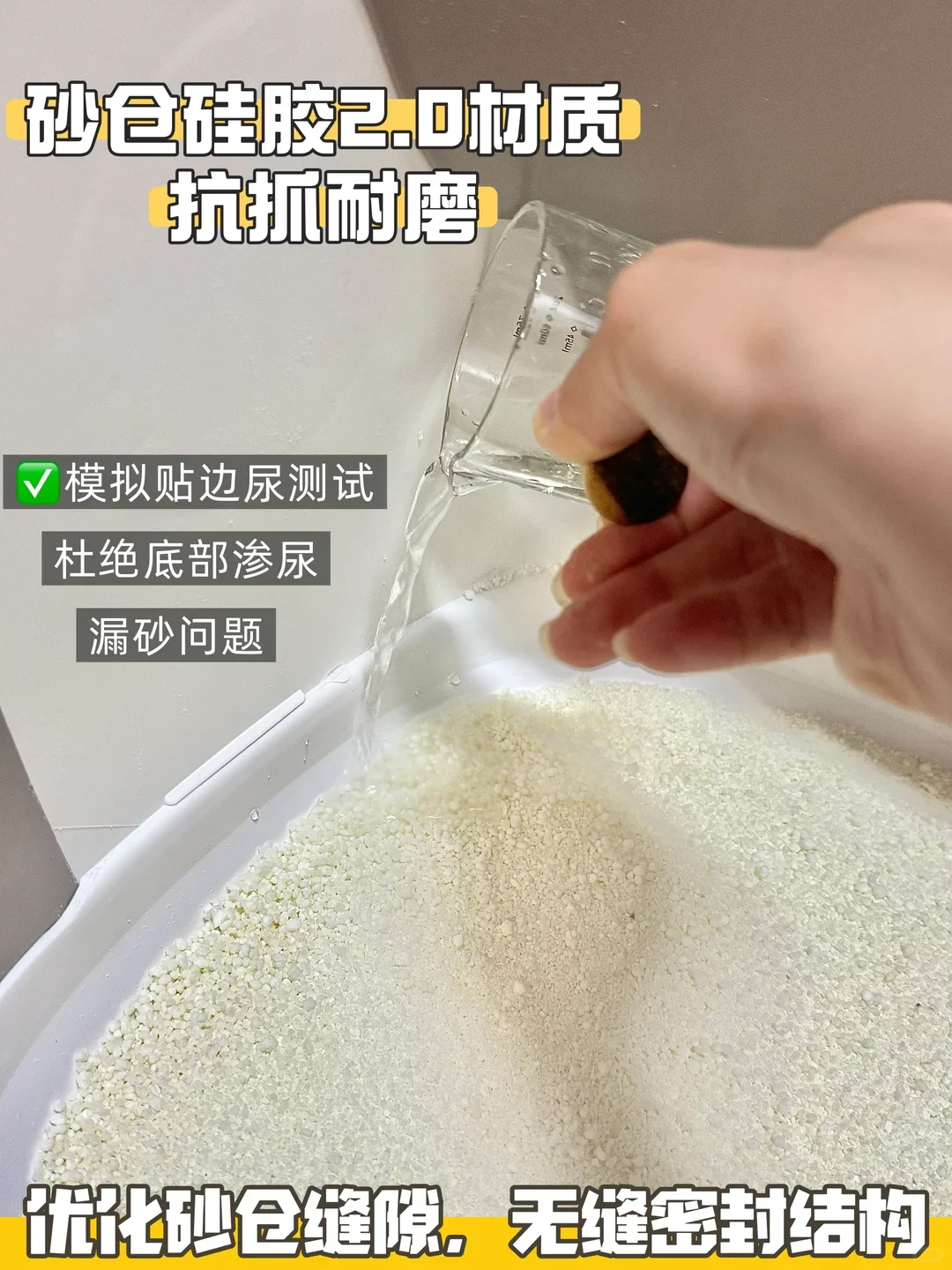 A hand pours water from a small measuring beaker down the inner curved wall of a cat litter box filled with white mineral litter, demonstrating water-resistance along the inner seams.