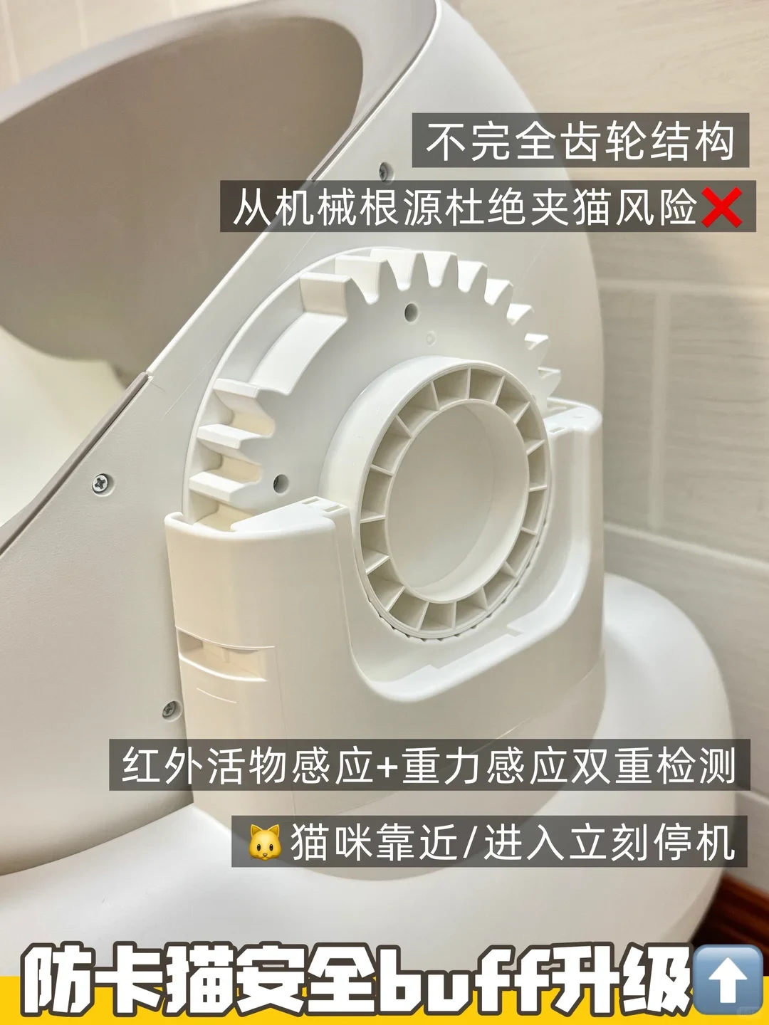 A close-up photograph of the side mechanism of a white automatic cat litter box, displaying a large incomplete gear structure, designed to prevent cat entrapment. Descriptive text overlays explain its mechanical safety features and sensors.