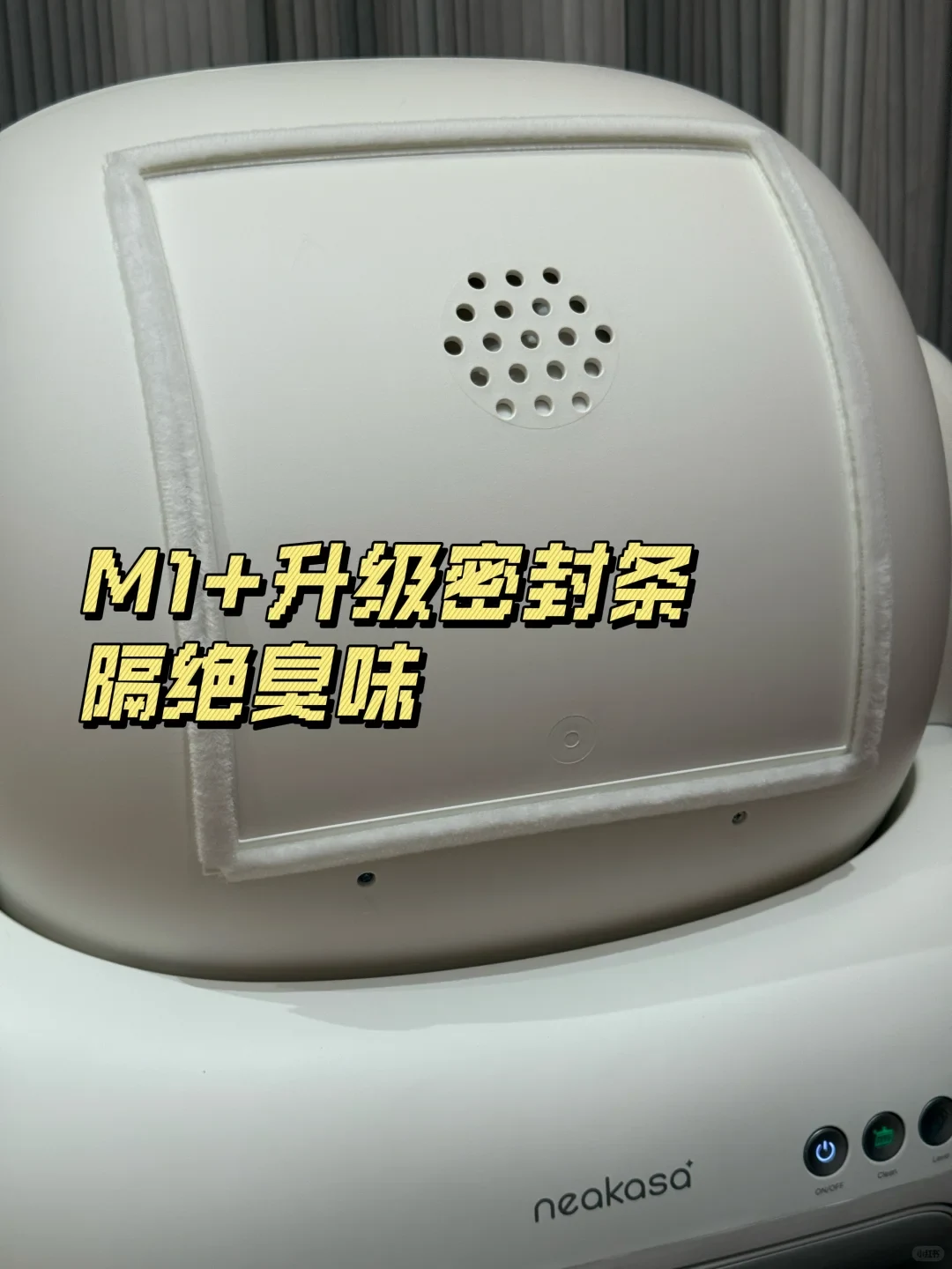 Close-up view of a white Neakasa automatic cat litter box showing a square compartment surrounded by a white sealing strip and a ventilation hole cluster.