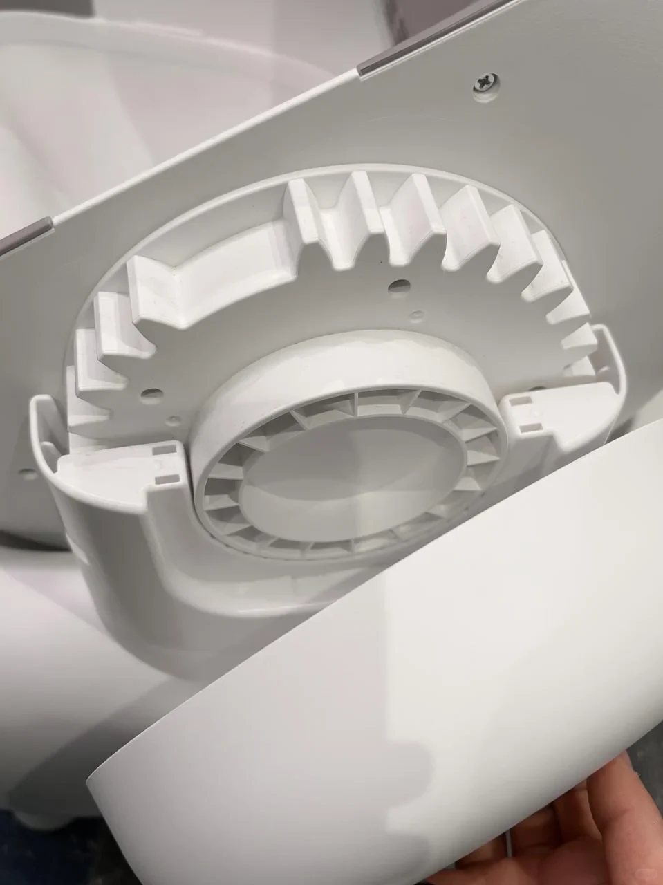Close-up view of the white plastic gear mechanism inside the partially disassembled automatic cat litter box.