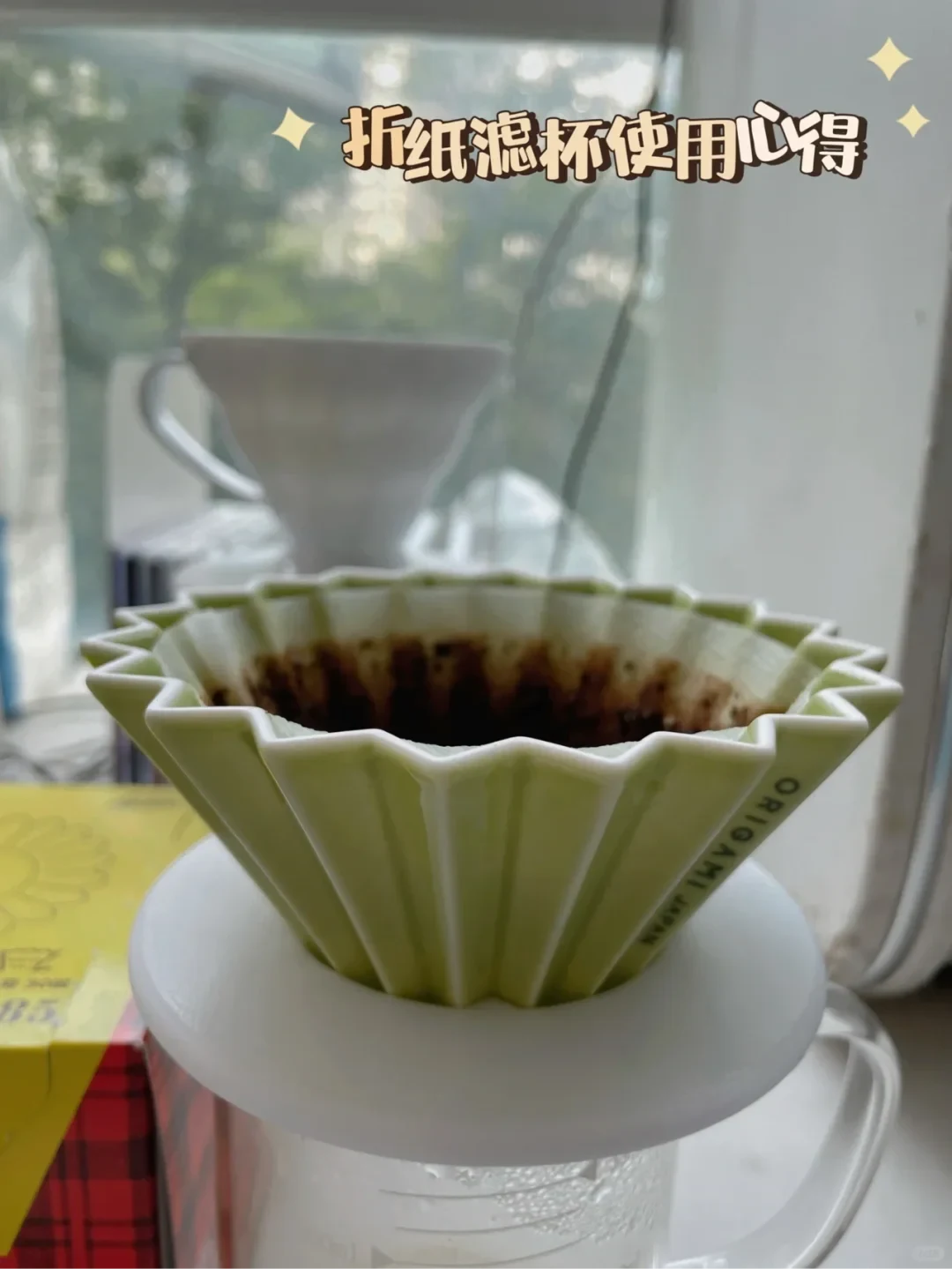 A green, fluted coffee dripper holding a used paper filter and coffee grounds sits over a white vessel. Chinese text at the top reads “Thoughts on using the Origami filter dripper.”