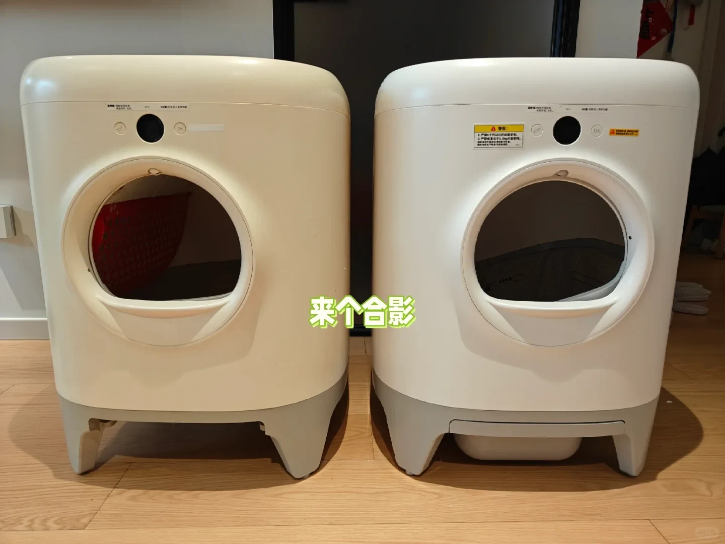 Two robotic cat litter boxes placed side by side on a light wood floor, one showing slight yellowing on the left and a newer white unit on the right, with green Chinese overlay text between them.
