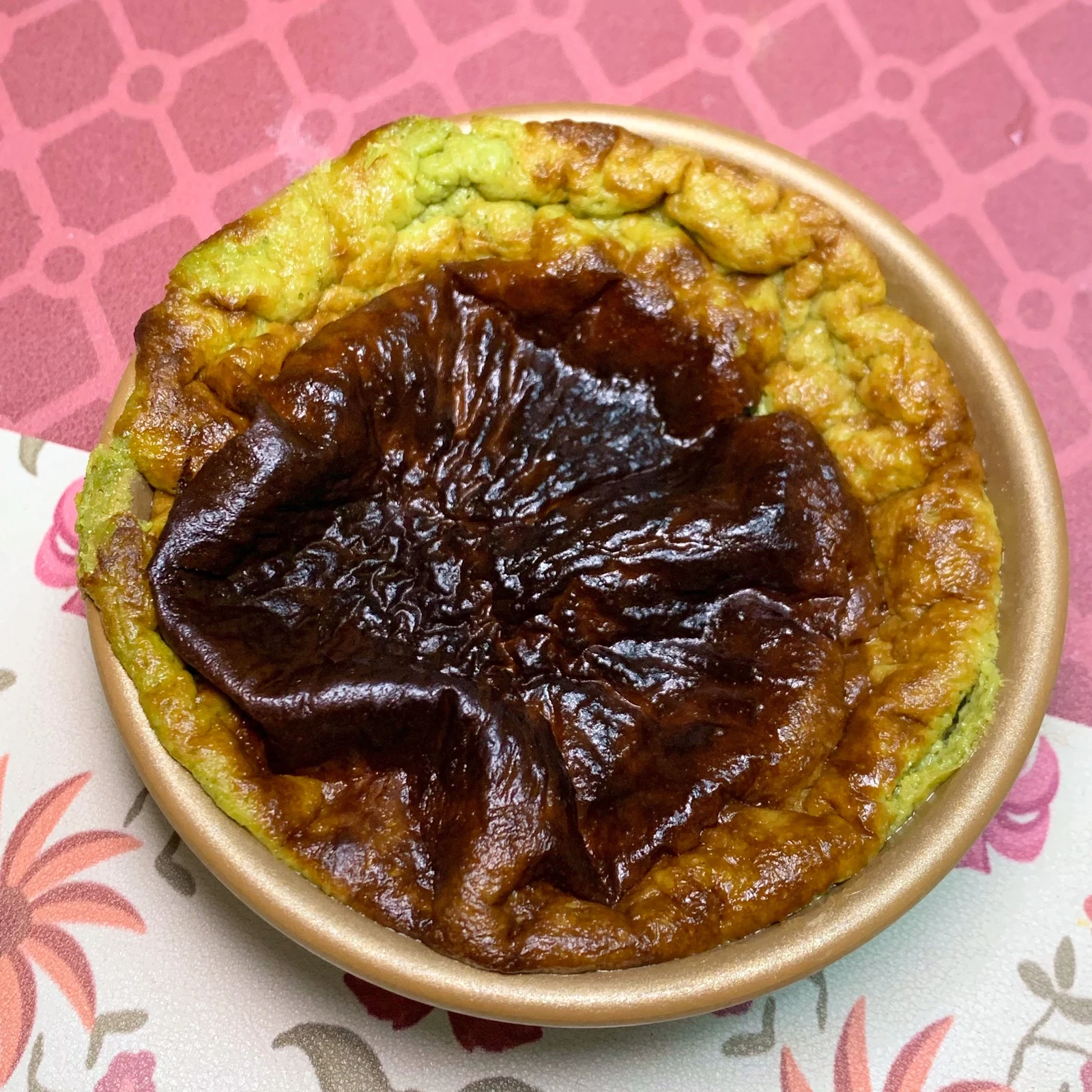 A green cheesecake with a browned centre.