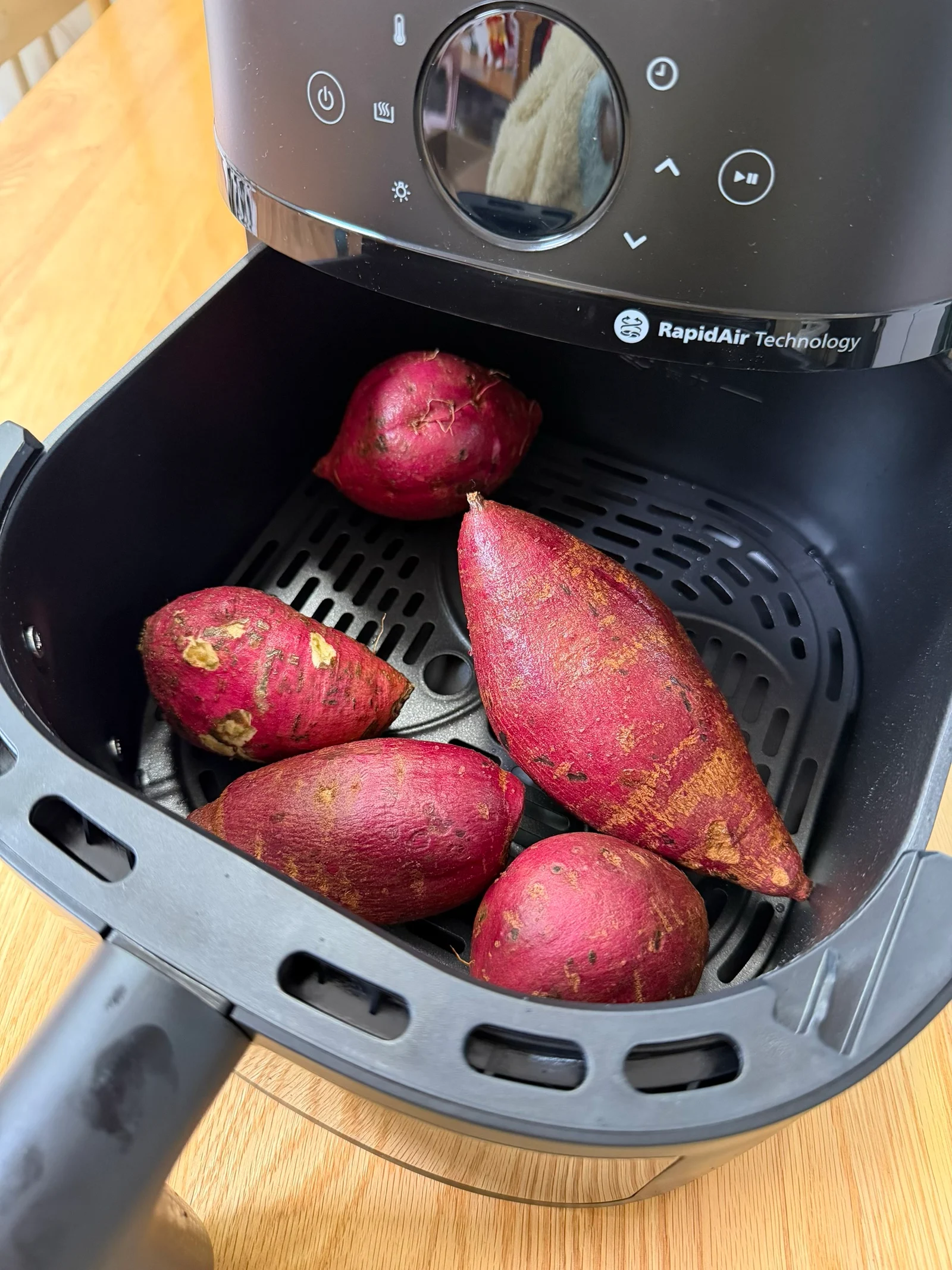 Several sweet potatoes arranged in the NA230 basket before cooking.
