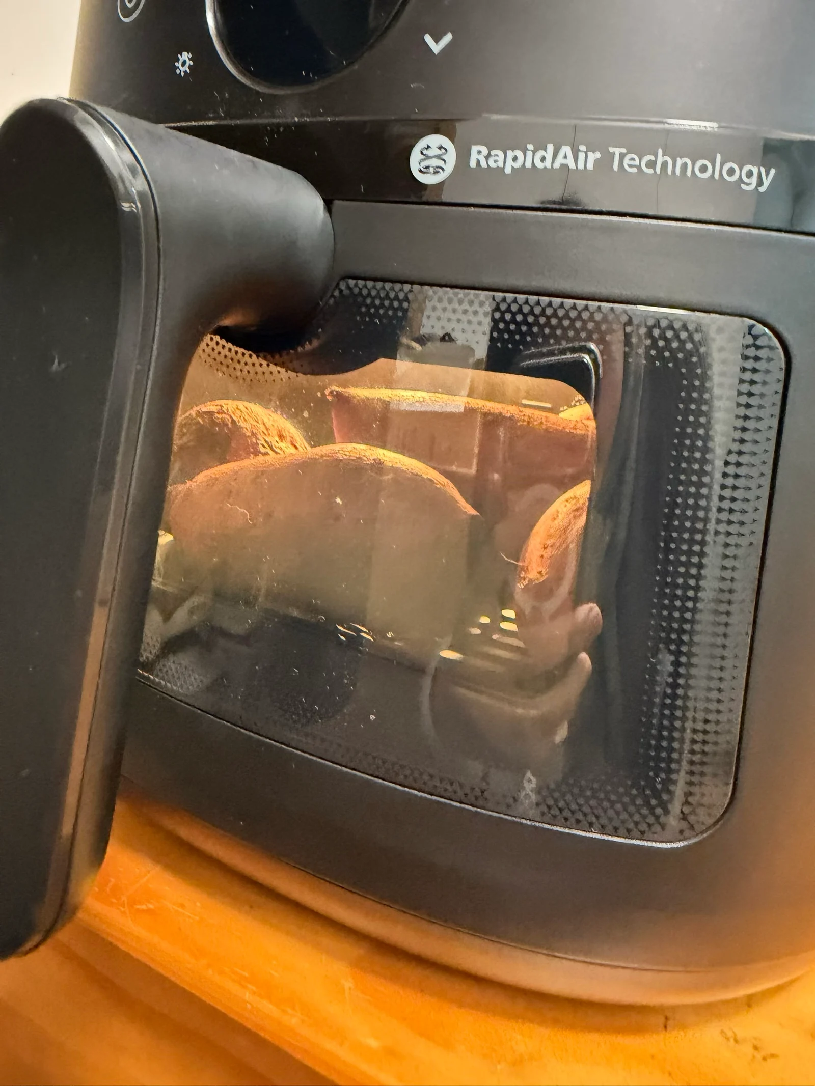 Sweet potatoes visible through the illuminated cooking window.