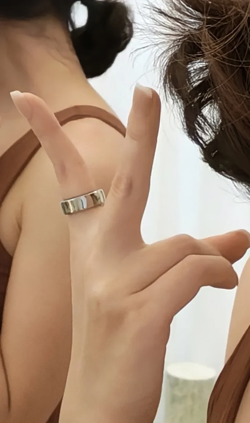 Close-up of a person's hand showing a wide silver band ring worn on the index finger.
