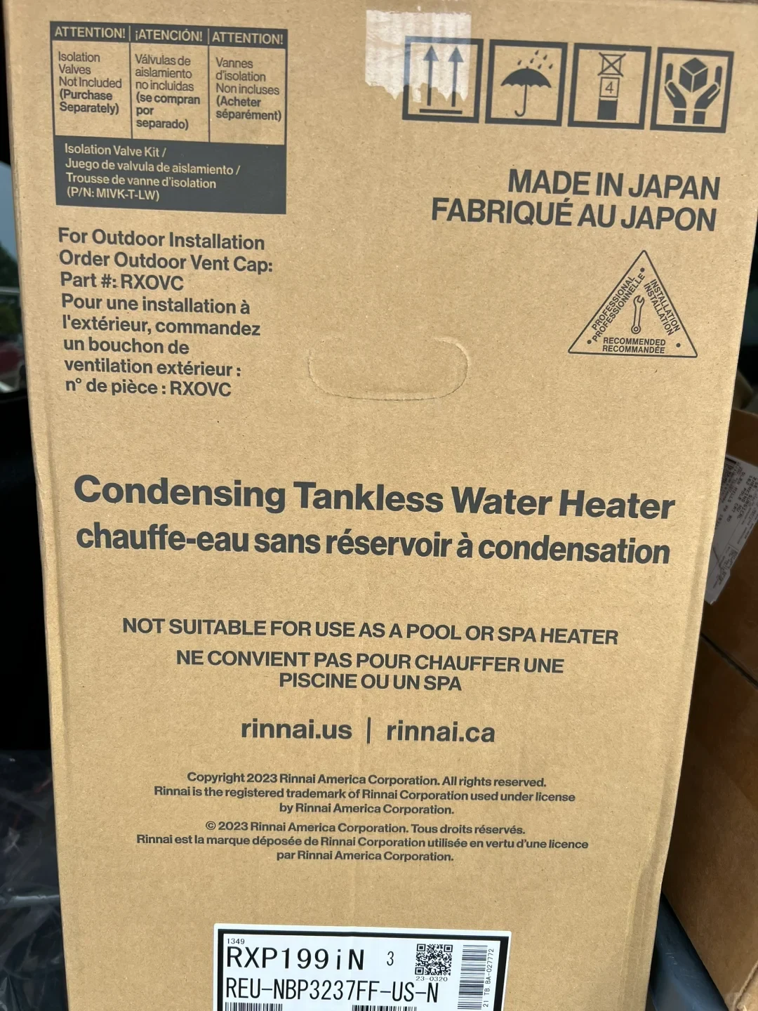 A cardboard Rinnai box for a condensing tankless water heater, marked “RXP199 iN” and “REU-NBP3237FF-US-N.” The box says isolation valves are sold separately, gives an outdoor vent cap part number, and warns the heater is not suitable for pools or spas.