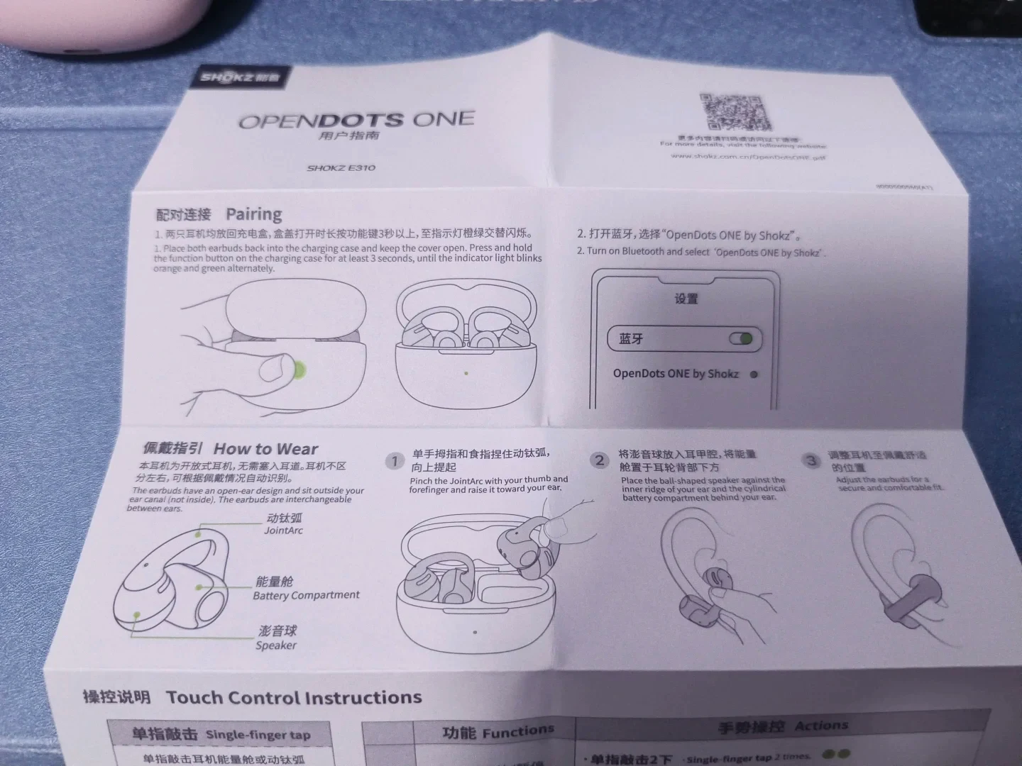 Printed user guide for the Shokz OpenDots ONE, showing illustrated diagrams and bilingual instructions for Bluetooth pairing, clip-on wearing, and touch controls.