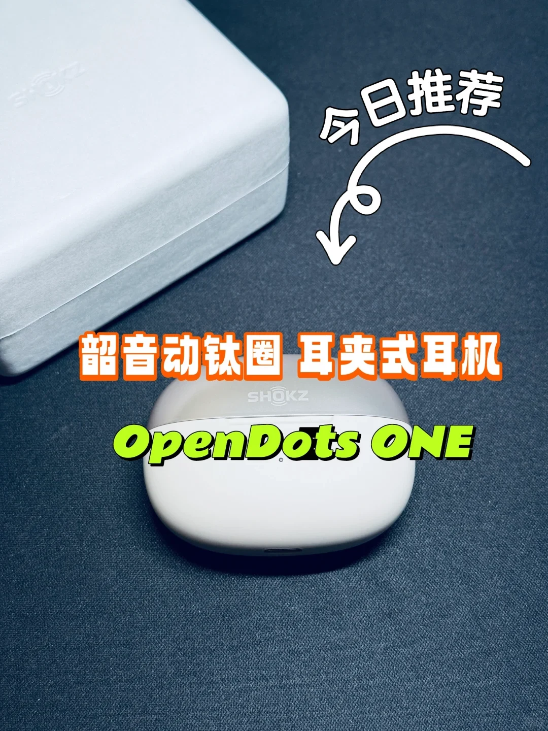 A Shokz OpenDots ONE ear-clip earphone charging case resting on a dark surface next to its packaging box, with overlay text recommending the product.