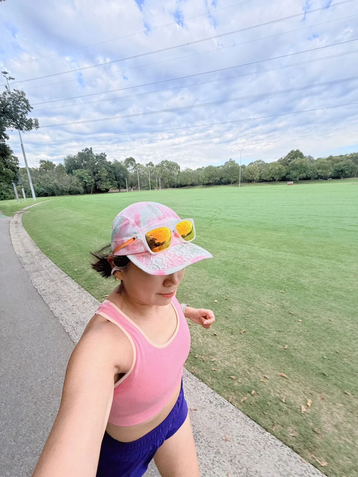 A source-post photograph of a runner in a pink top beside a track, with a white clip-on earbud visible.