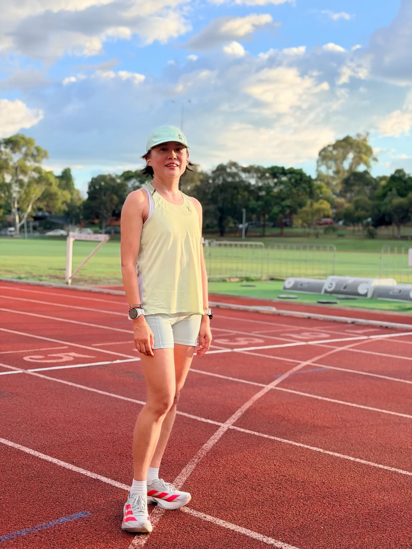 A source-post photograph of a runner in a green cap and yellow top on a running track.