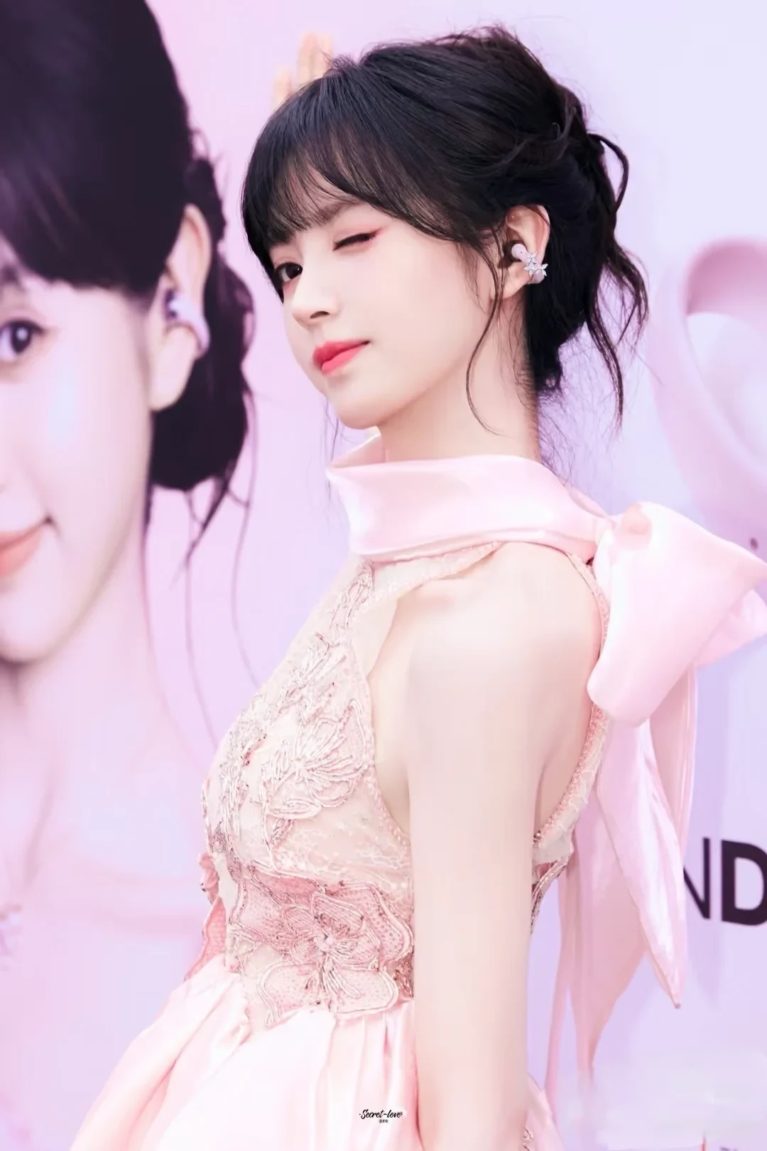 A promotional-style portrait included in the source post, showing a person in a pink dress wearing a clip-on earbud.