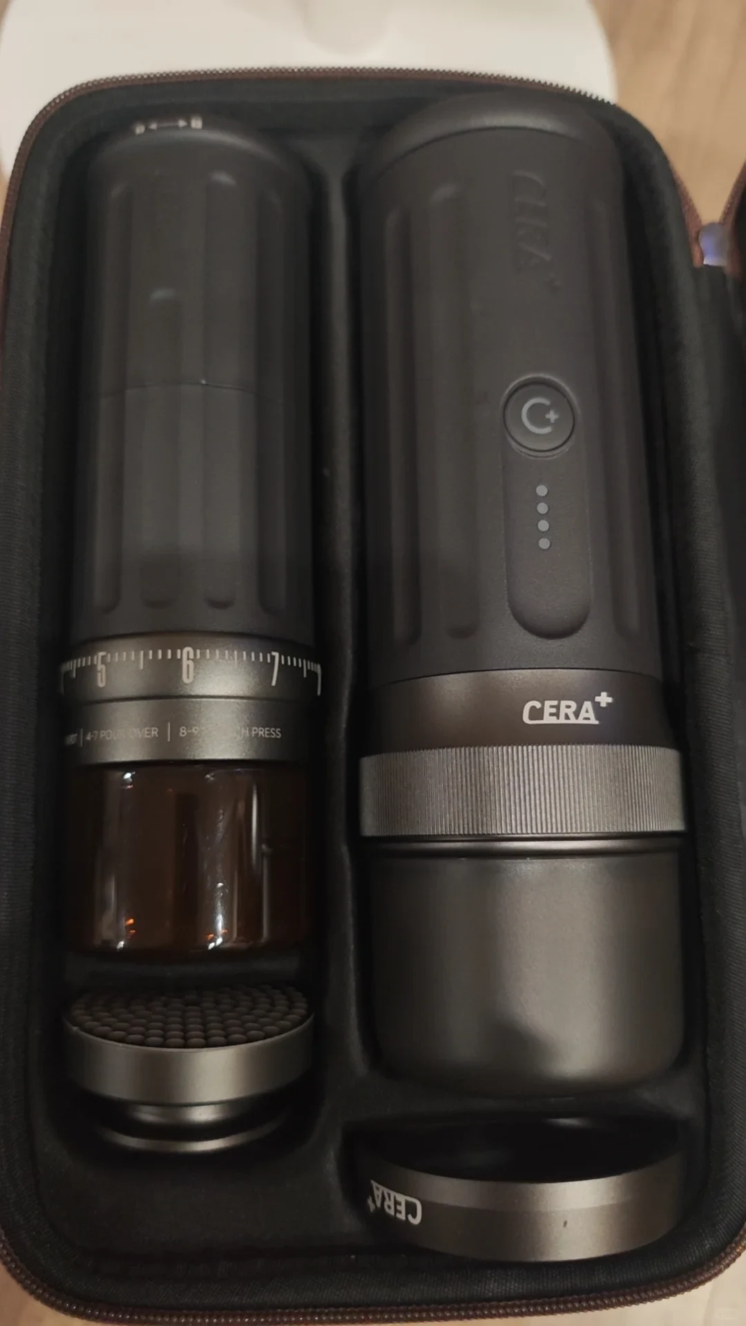 A CERA+ coffee grinder on the left and a portable espresso maker on the right fit together in a zippered carrying case.